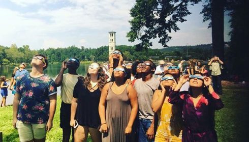 Group of students with solar eclipse glasses looking up at sky