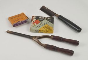 Photo of Curling tongs, straightening comb, pot of hair pomade and two boxes of hairpins, 1930s